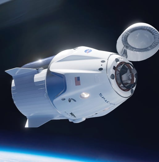 A white NASA space capsule with the american flag on it. The top of the capsule is open and the capsule is flying in space.